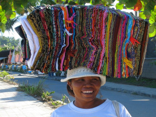 Indonesia, Bali, Padang Bay, Woman carrying Sarongs for sale on here head
